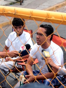 Ariel Varela speaks from behind the police barricade at the start of the Indignado hunger strike